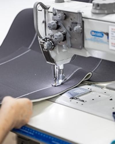 Precision stitching of grey denim seat cover fabric using an industrial sewing machine.